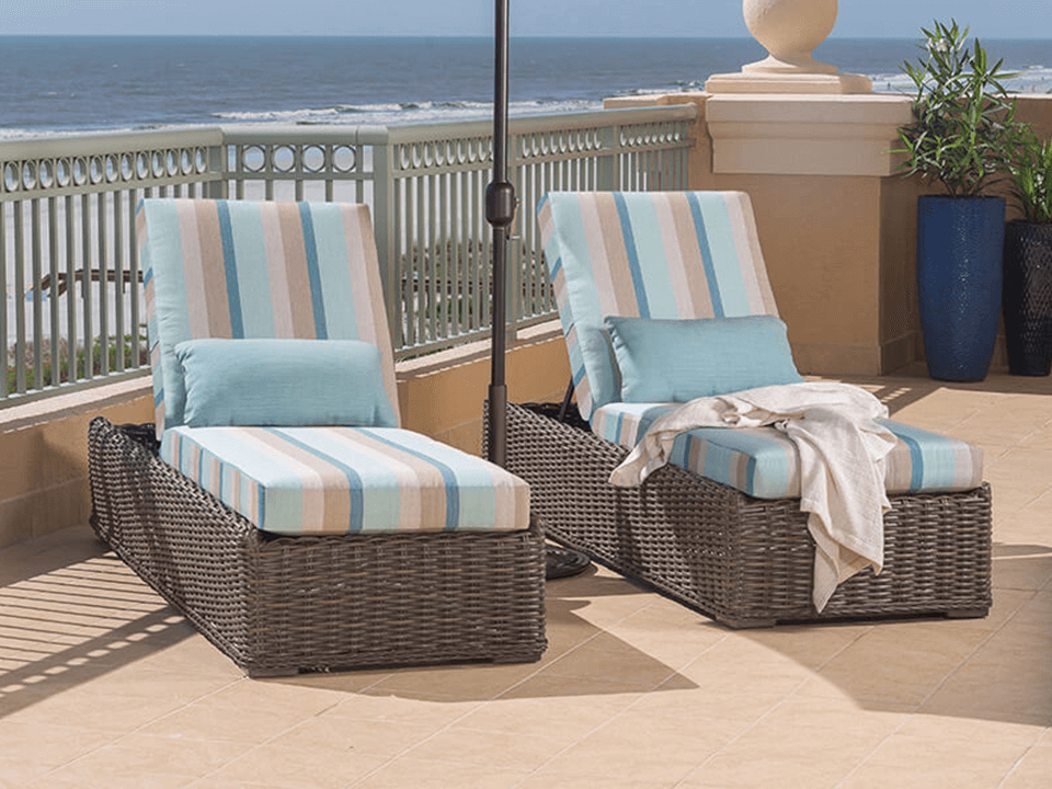Resin wicker pool loungers with bright orange cushions lined along a covered patio, showcasing resort-style outdoor furniture.